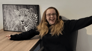 Sharon in haar woonkamer met een schilderij van de weggeefhoek